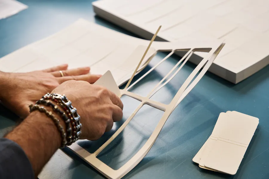 Operatore CO&IN al lavoro manuale su cartellini personalizzati, con attenzione artigiana a pieghe, forature e finiture per packaging premium.