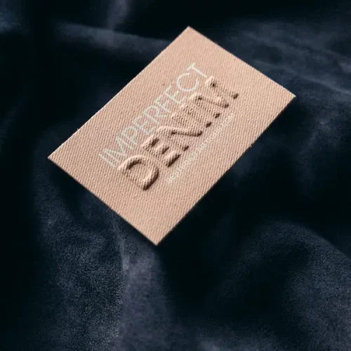 Etichetta CO&IN stampata su nastro denim marrone naturale, con design personalizzato e finiture precise per abbigliamento e accessori Made in Italy.