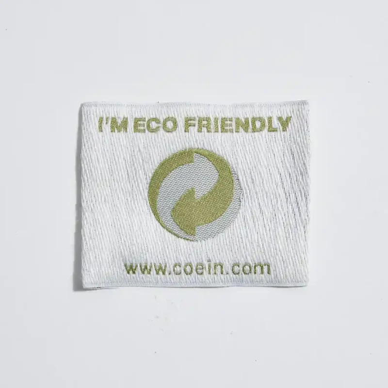 Etichetta tessuta con fondo in canapa e broccati in poliestere, personalizzazione eco-friendly e resistente per prodotti di alta qualità.